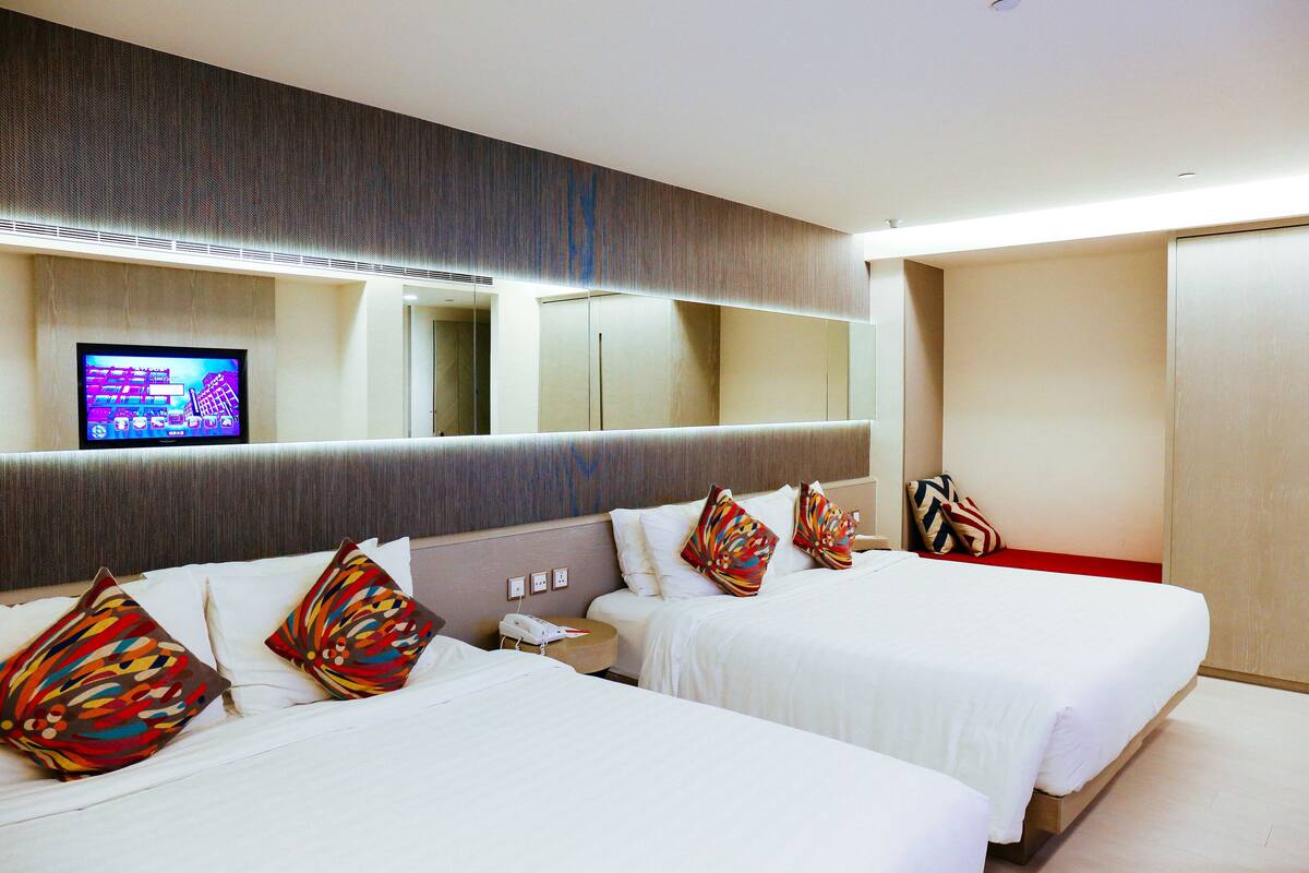 Une chambre d’hôtel avec deux lits, une télévision et un miroir.