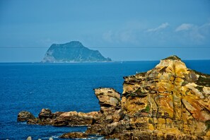 Un paysage côtier caractérisé par d’imposantes formations rocheuses et une île visible au loin.