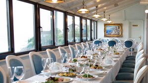 A long dining table with white tablecloths, blue chairs, and multiple wine glasses and plates set for a meal. - Hotel Kolyda (Sovinion)