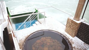 A hot spring area with a view of the sea, a stone basin, and a glass railing. - Hotel Kolyda (Sovinion)