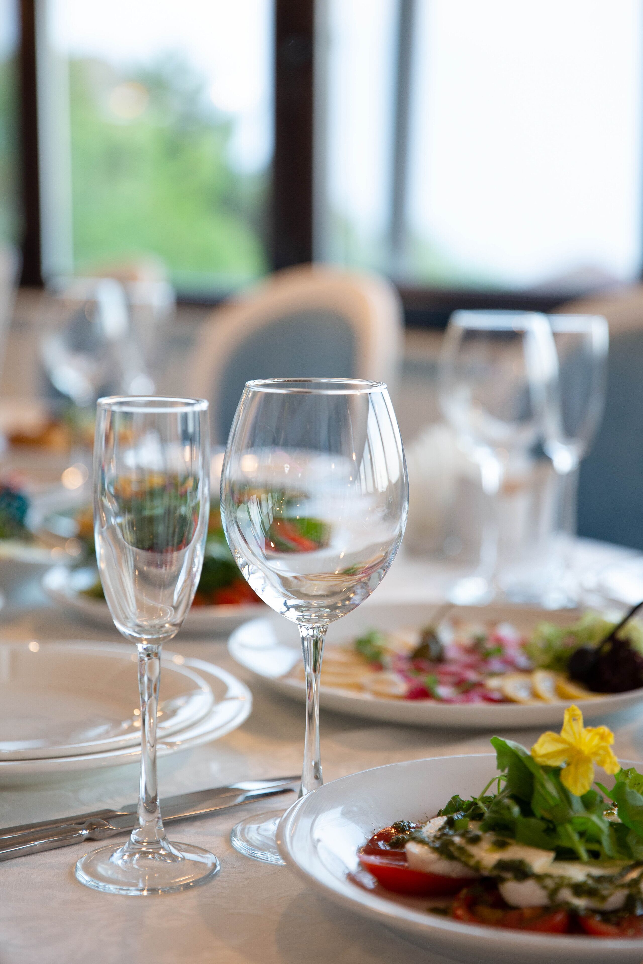 A dining table with empty wine glasses and plates with food.