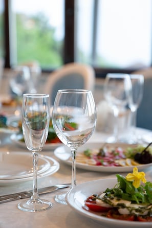 Una mesa de comedor con copas de vino vacías y platos con comida.