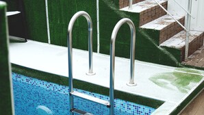 A swimming pool with a metal ladder, steps leading to a higher level, and a white railing. - Hotel Kolyda (Sovinion)