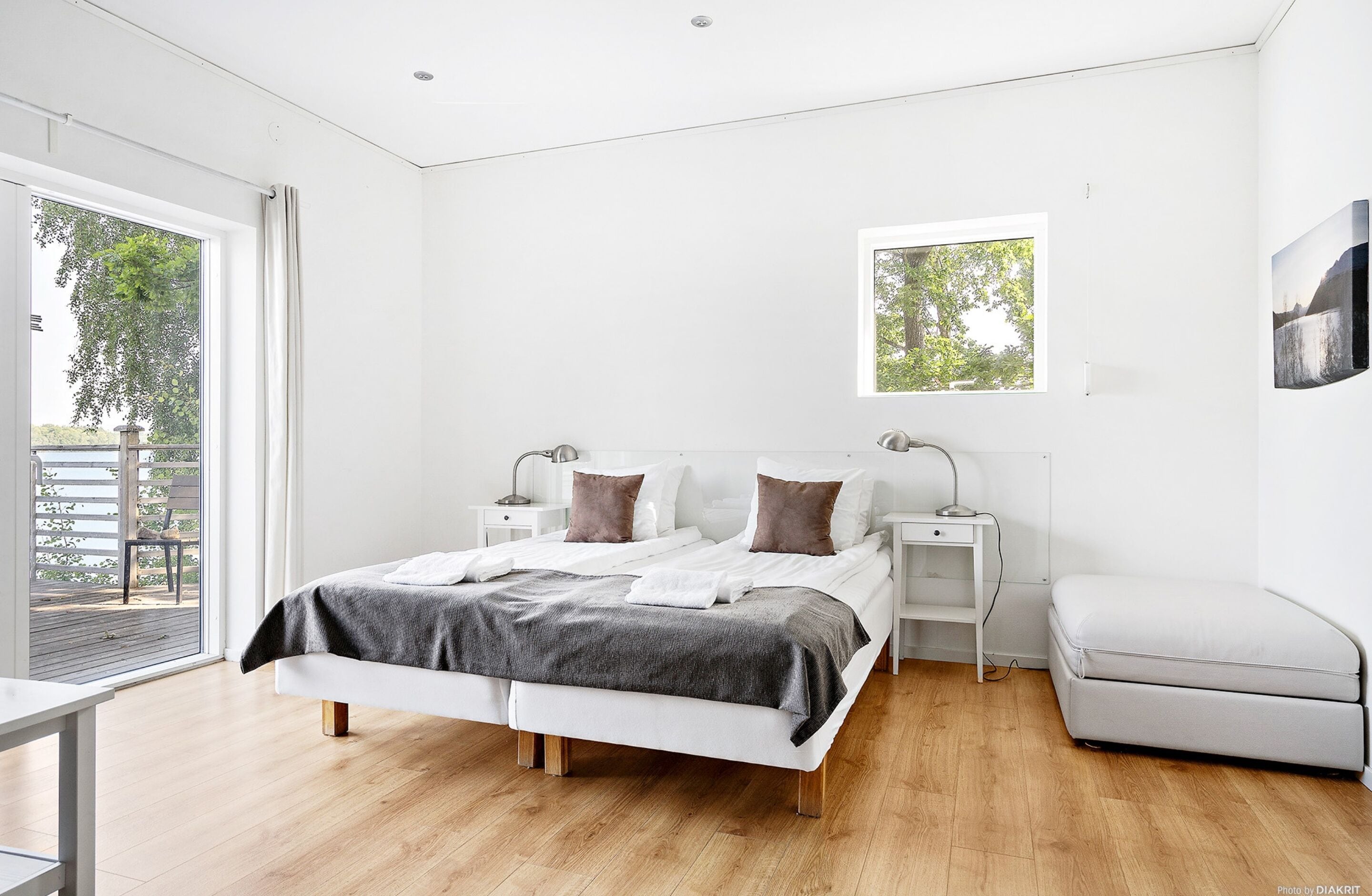 A modern bedroom with a large bed, bedside tables, a window, and a view of greenery outside.