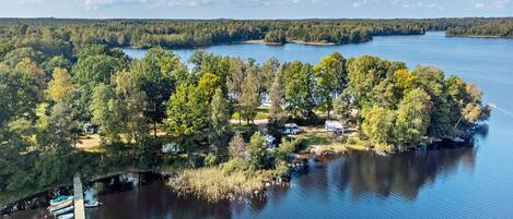 An aerial view of a lakeside property with a dock, boats, and RVs.