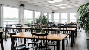 Un comedor amplio con ventanas grandes, mesas de madera y sillas negras.