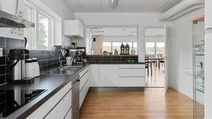 Una cocina moderna con armarios blancos, encimera negra y suelo de madera.