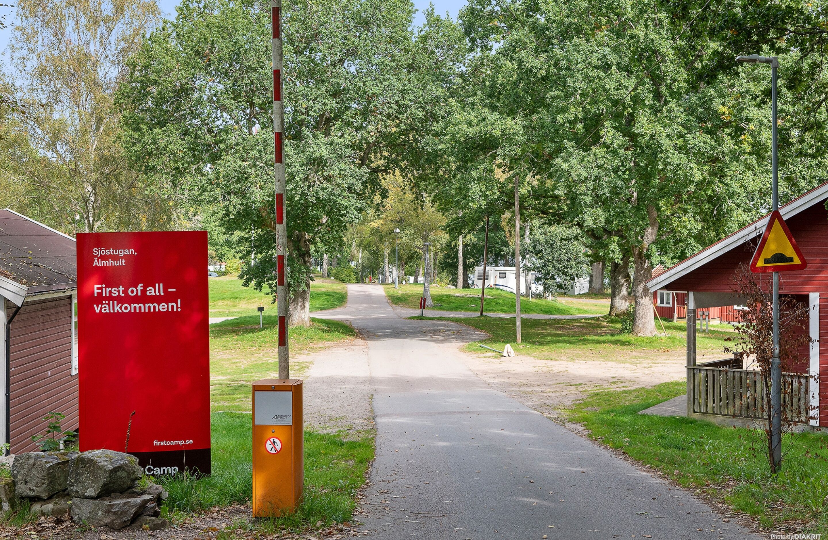 A pathway leading to a red building with a sign reading "First of all - welcome!" and a no parking sign.