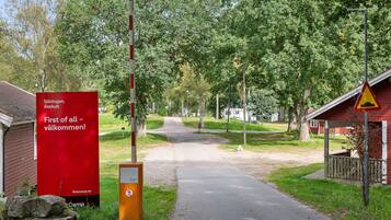 A pathway leading to a red building with a sign reading "First of all - welcome!" and a no parking sign.