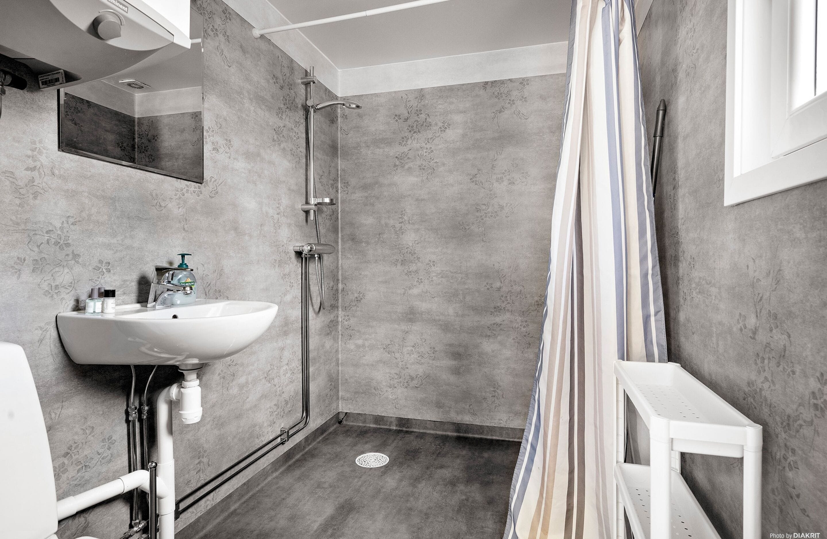 A bathroom with a shower, a sink, and a mirror.