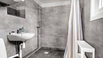 A bathroom with a shower, a sink, and a mirror.