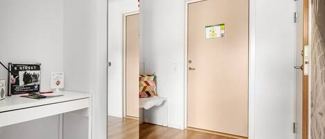 A hallway with a white desk, a door with a safety sign, and a bench with a colorful cushion.