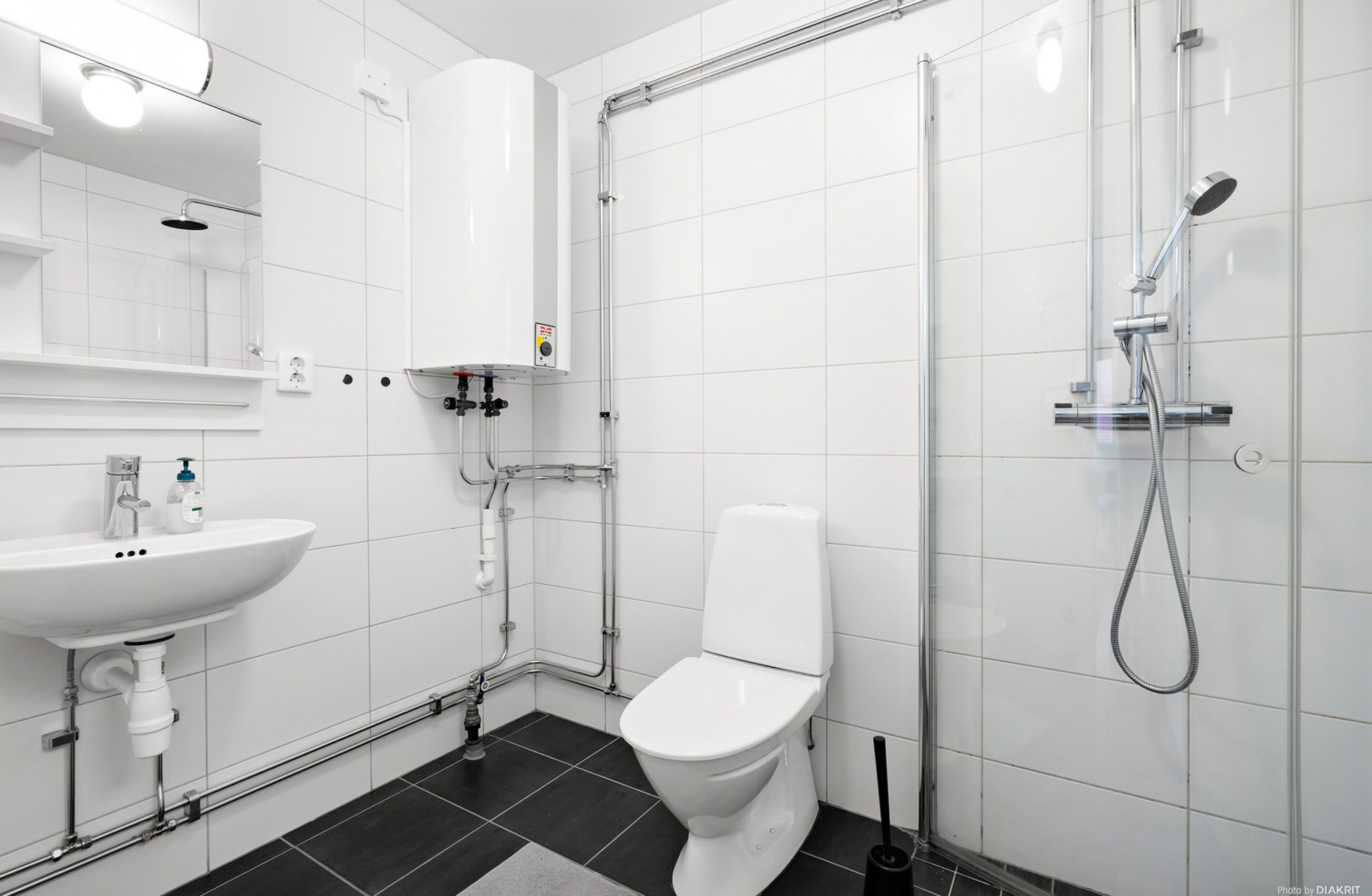 A modern bathroom with a white sink, toilet, and shower.