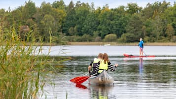 Ein ruhiger See mit zwei Kanus, eines davon mit zwei Personen und das andere mit einer Person.