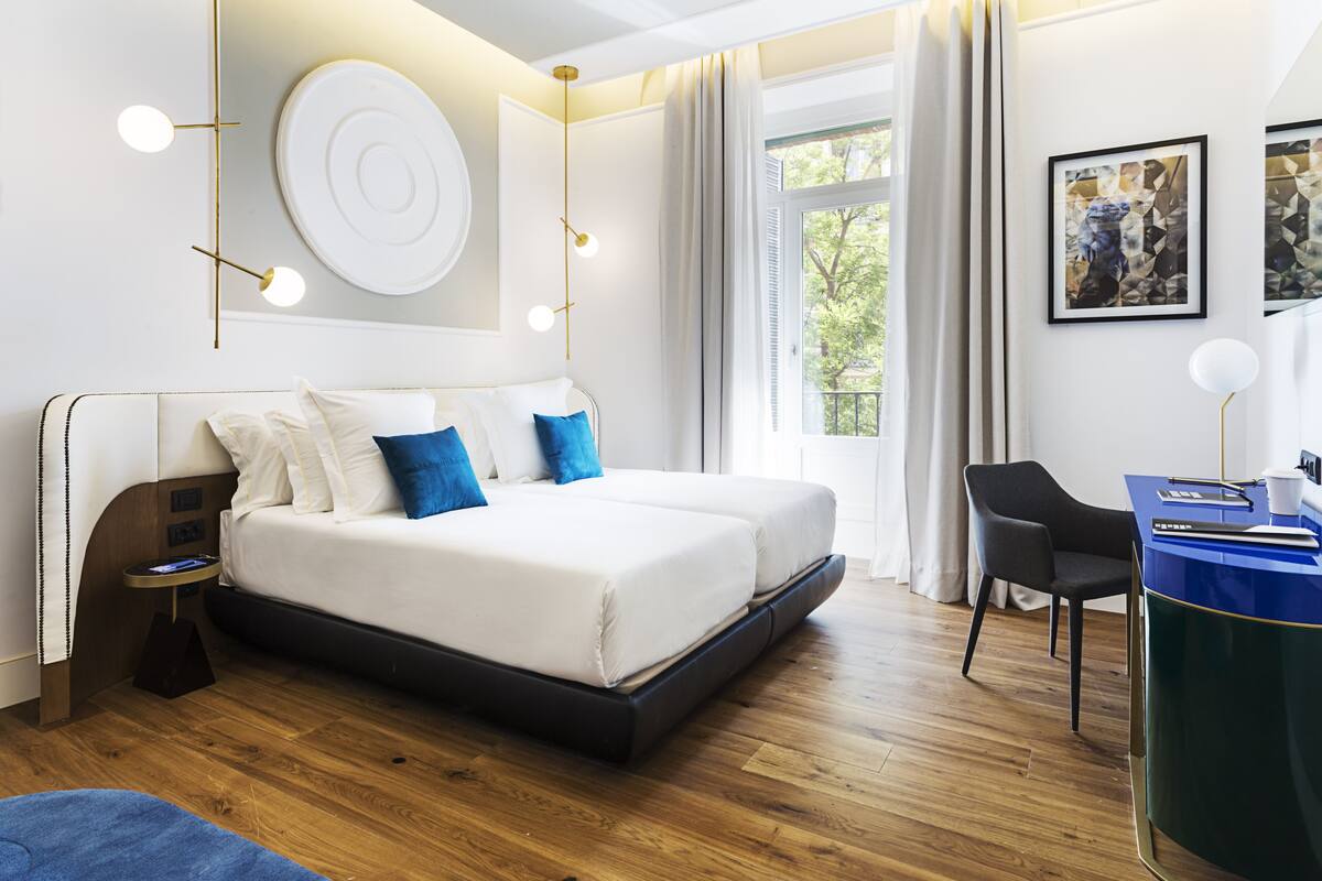 Ein modernes Schlafzimmer mit einem großen Bett, Nachttischen, einem Schreibtisch und Blick ins Freie.
