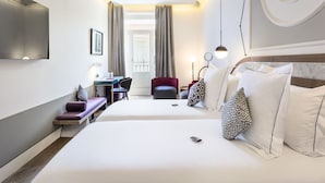 Une chambre d’hôtel avec deux lits, un bureau, une chaise et un téléviseur fixé au mur.