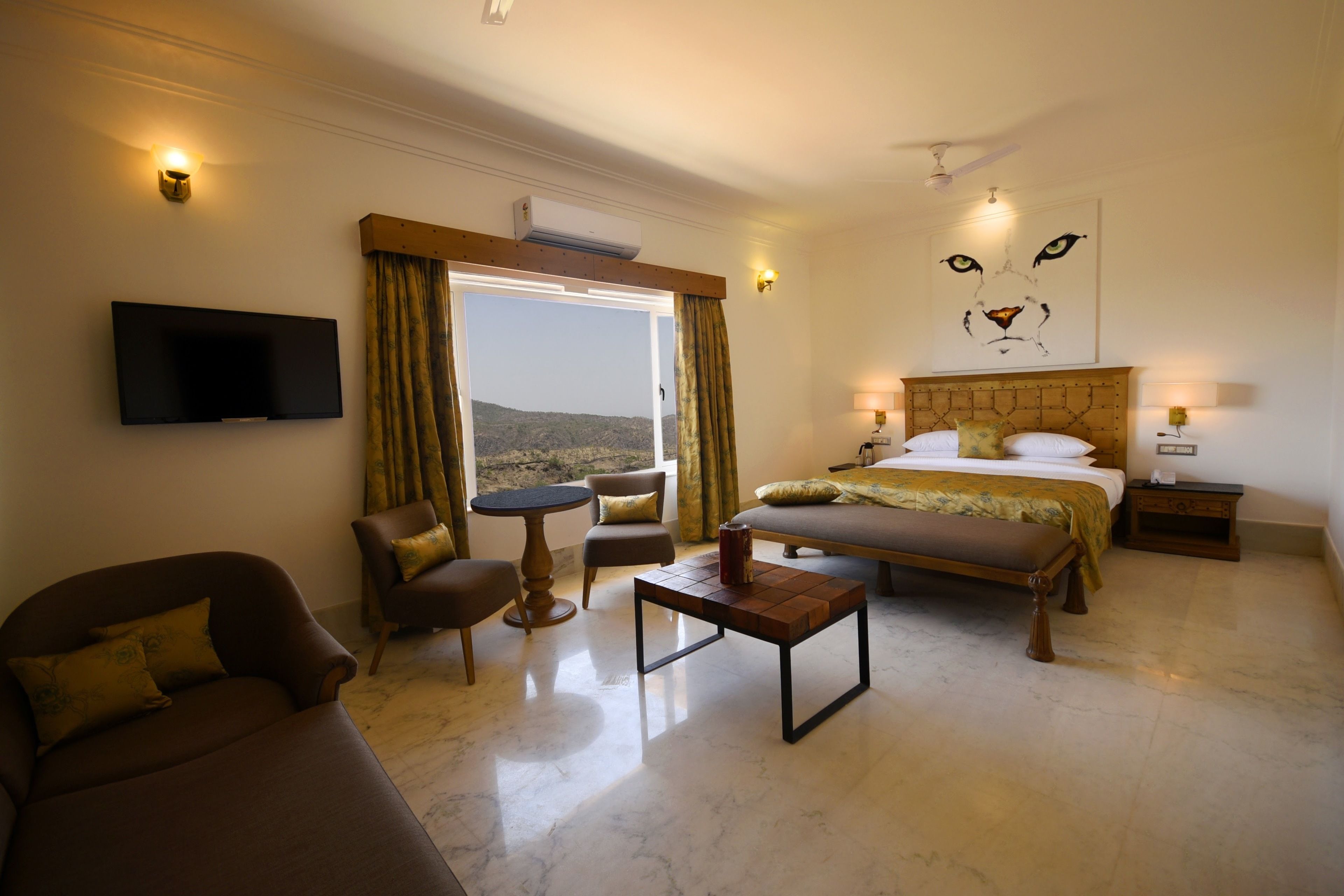 Habitación de hotel con cama, sofá, una mesita, televisor y vistas al exterior.