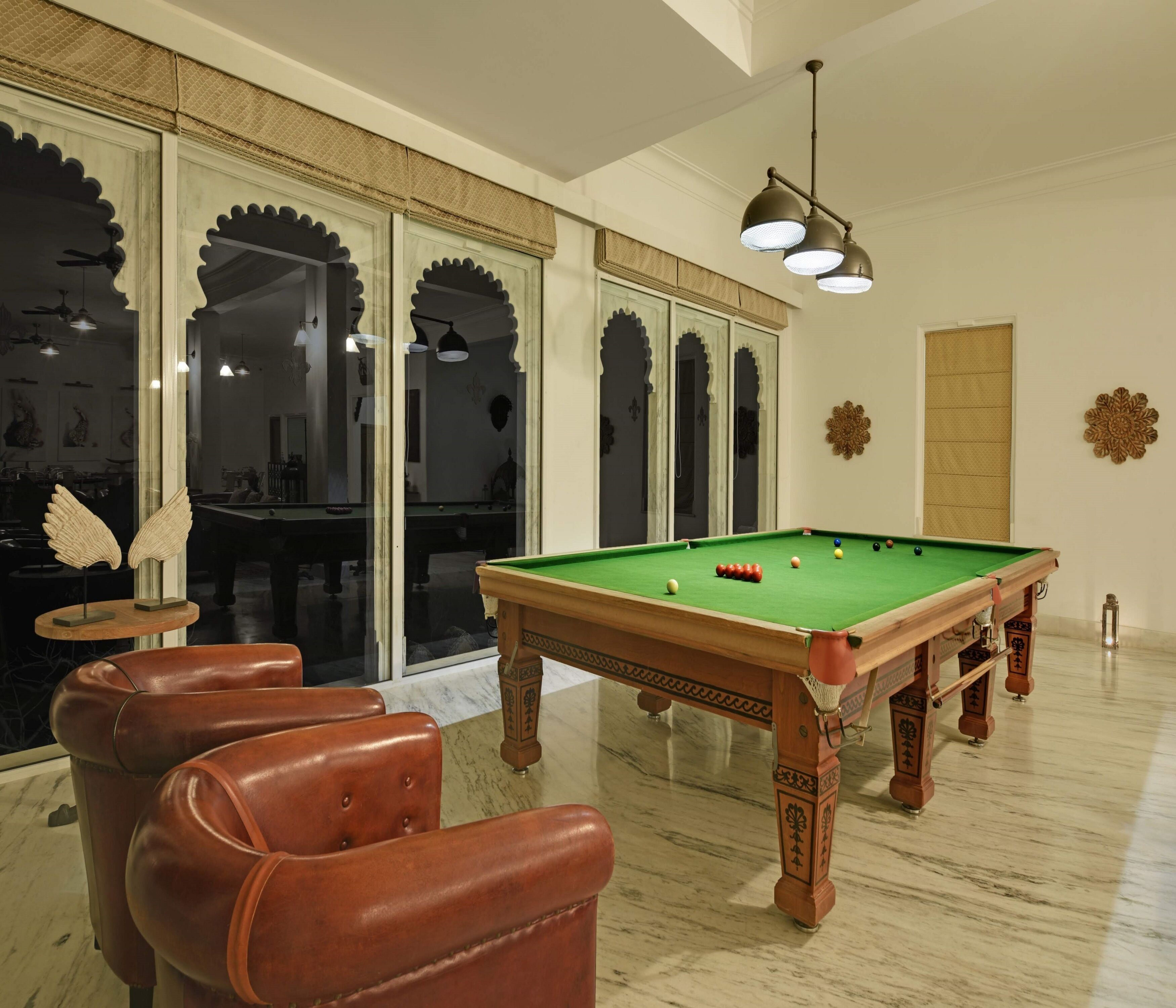 A billiards room with a pool table, leather chairs, and decorative wall art.