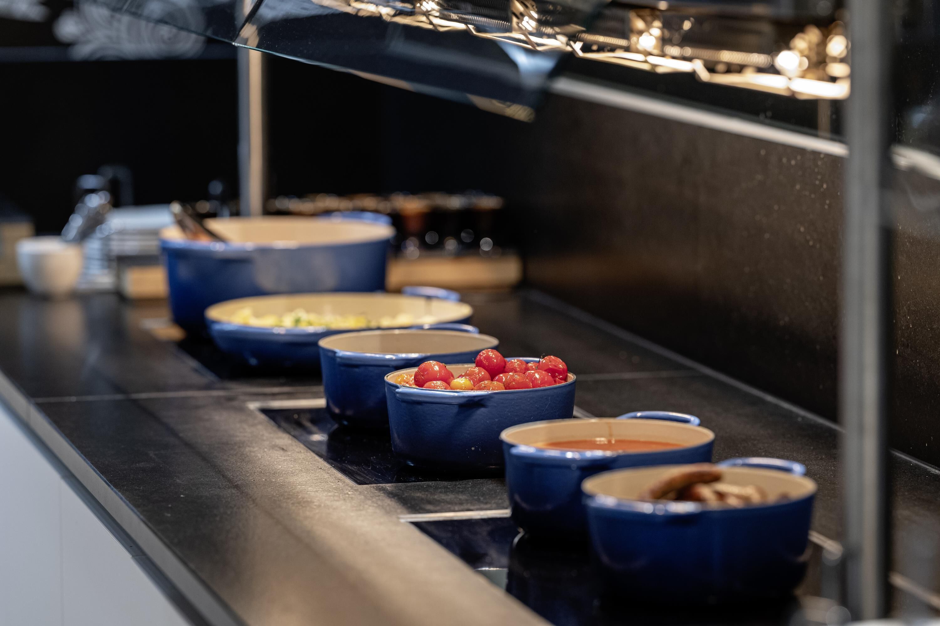 Una barra de buffet con diferentes platos servidos en boles azules.