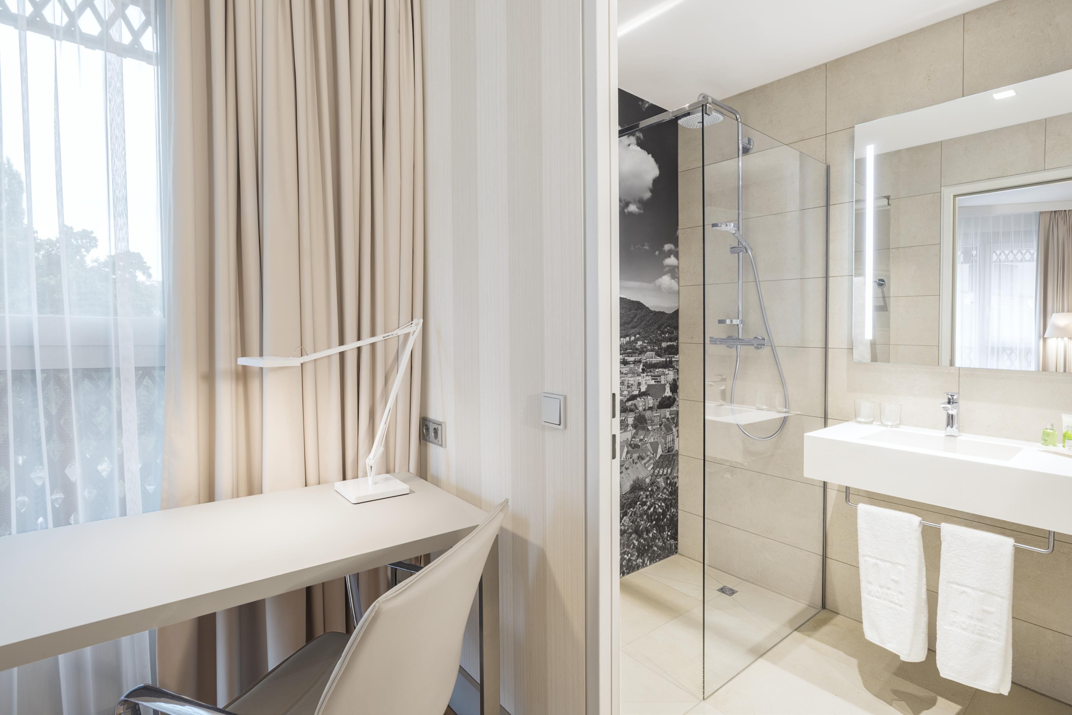 Un baño moderno con cabina de ducha de vidrio, lavamanos blanco y un espejo grande.