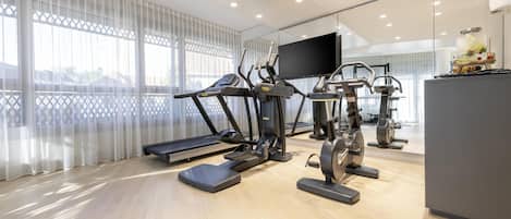 A modern home gym with treadmills, elliptical machines, and a stationary bike.