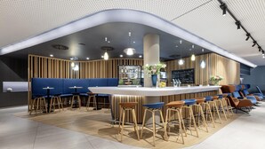 Eine moderne Bar mit gewölbter Decke, Holzleisten und blauen Sitzmöglichkeiten.