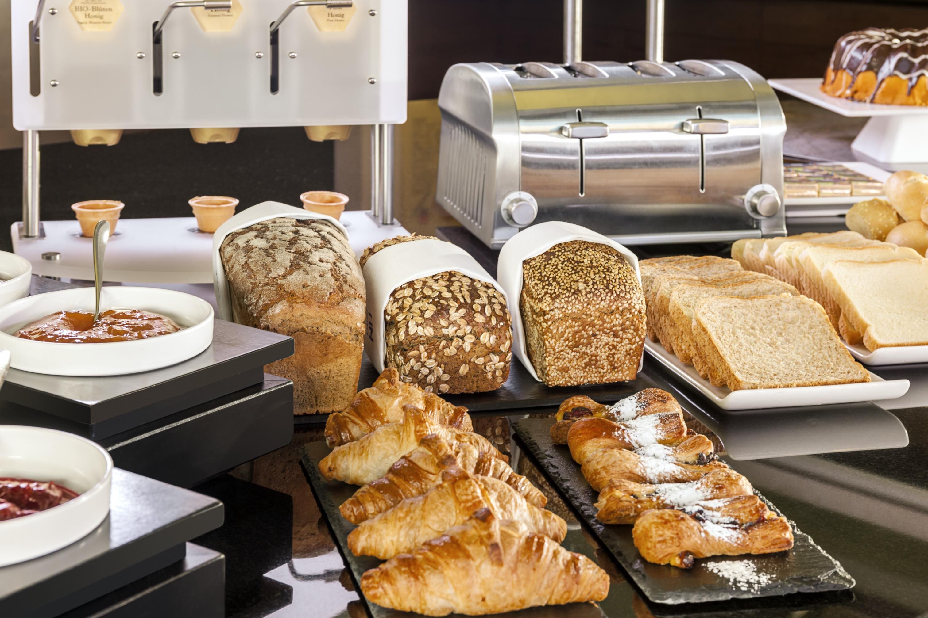 Un bufé de desayuno con panes, pasteles y una tostadora.