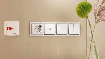 A wall-mounted electrical panel with a smoke detector and a power outlet.
