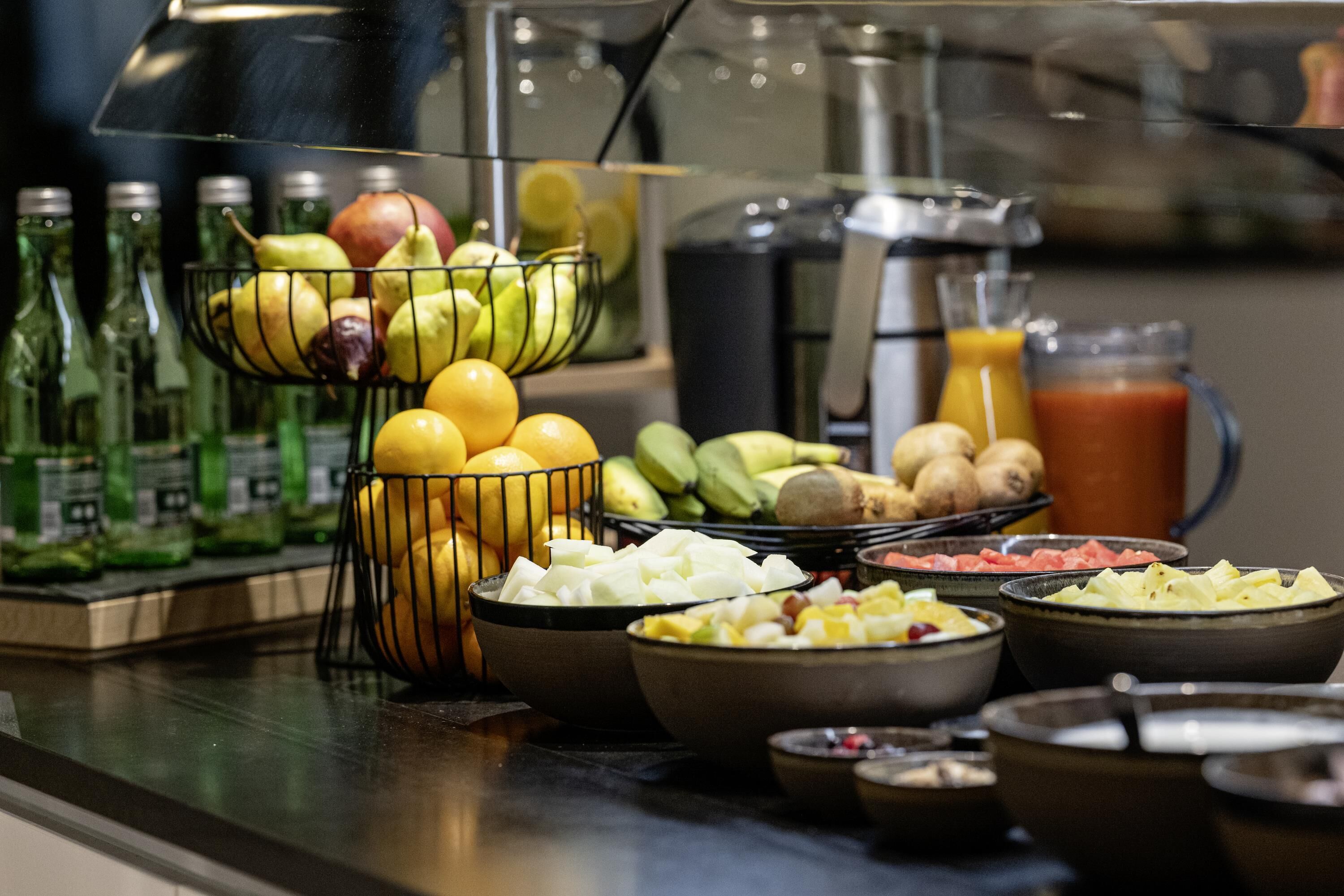 Un bufé con diversas frutas, verduras y bebidas.