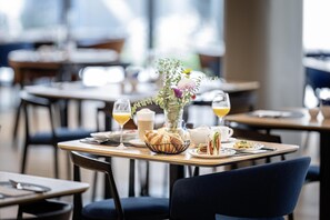 A dining area with tables set for breakfast, including croissants, sandwiches, and beverages. - NH Graz City (Graz)
