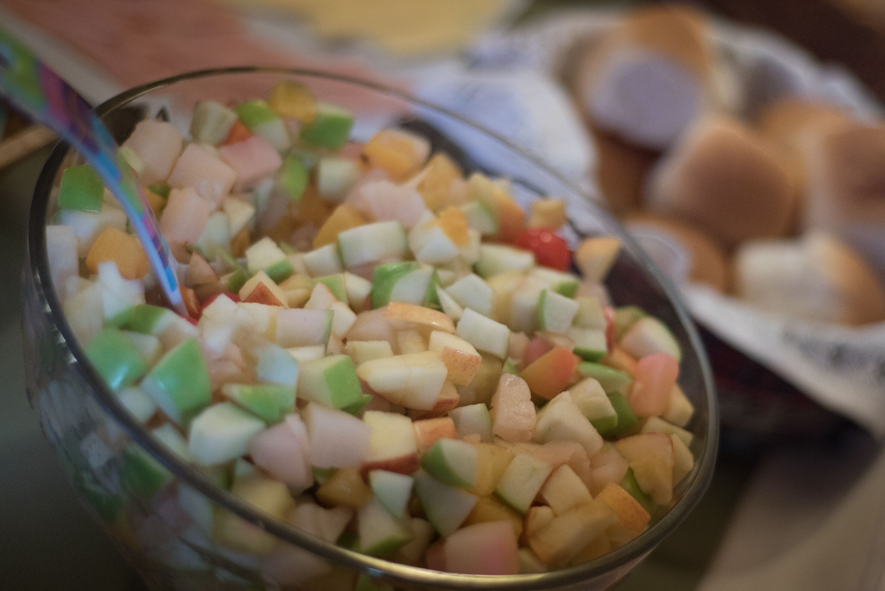 A bowl of diced fruit salad with a spoon.