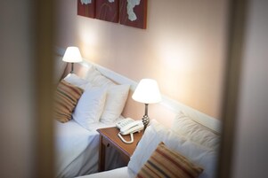 Habitación de hotel con dos camas, cada una con mesita de noche, lámpara y teléfono.