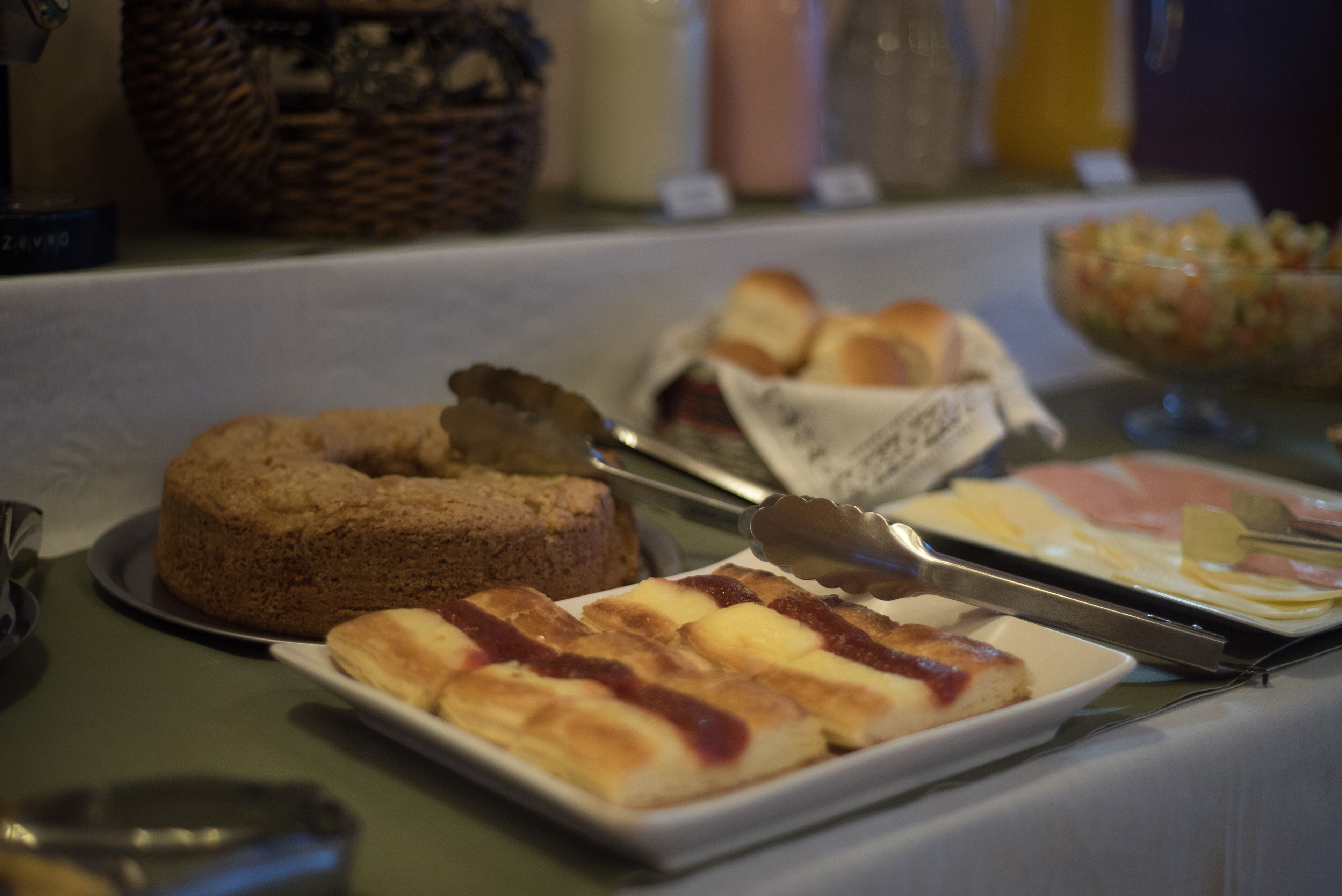 A buffet table with various food items including a cake, pastries, and a fruit salad.