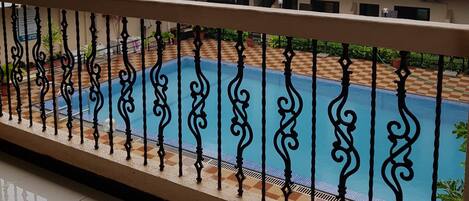 A building with a pool, a balcony, and a view of the sky.