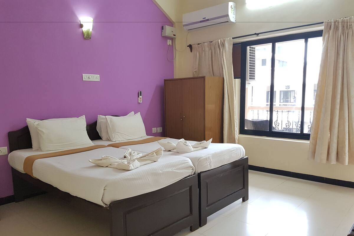 Une chambre d’hôtel équipée d’un lit, d’une armoire, d’une fenêtre avec des rideaux et d’un appareil de climatisation.