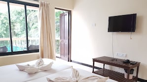 A hotel room with two beds, a TV on the wall, and a table with a phone and charger.