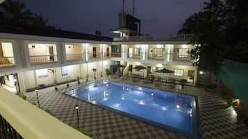 A hotel with a swimming pool, multiple balconies, and outdoor seating areas.