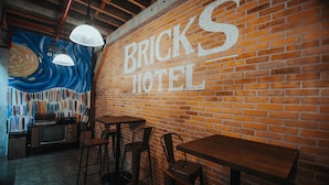 A brick wall with the text "BRICKS HOTEL" and a mural of a swirling pattern. There are tables and chairs arranged for dining. - The Bricks Hotel (Dumaguete)
