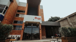 A hotel with a brick facade, a sign reading "The Bricks Hotel," and outdoor seating with tables and chairs. - The Bricks Hotel (Dumaguete)
