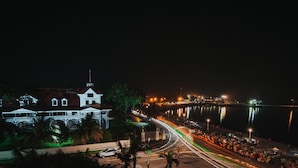 A waterfront hotel with a large building, a marina, and a busy street with light trails. - The Bricks Hotel (Dumaguete)