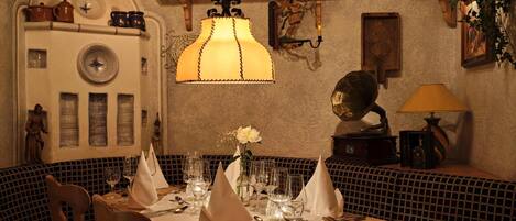 A dining area with a wooden table set for two, surrounded by patterned cushioned seating.