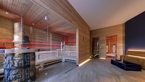 A modern sauna with wooden walls, a glass door, and a bench.
