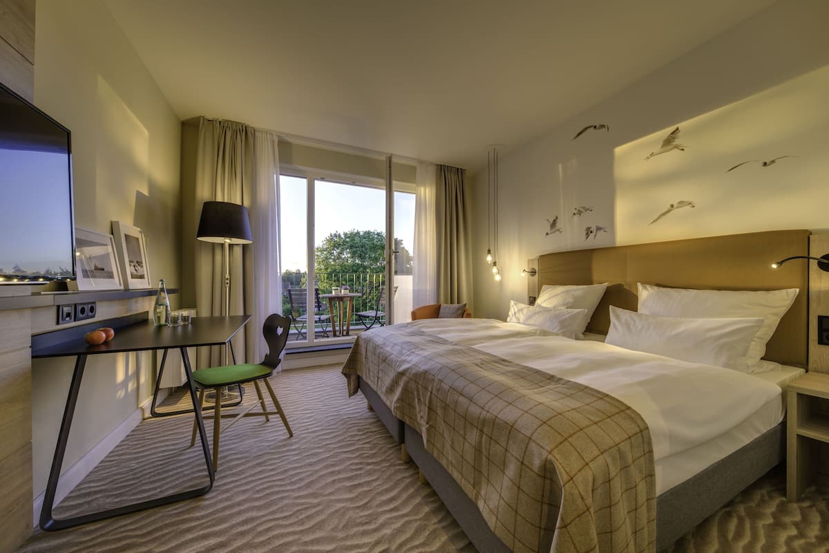 Ein Hotelzimmer mit Bett, Schreibtisch, Stuhl und Blick ins Freie.