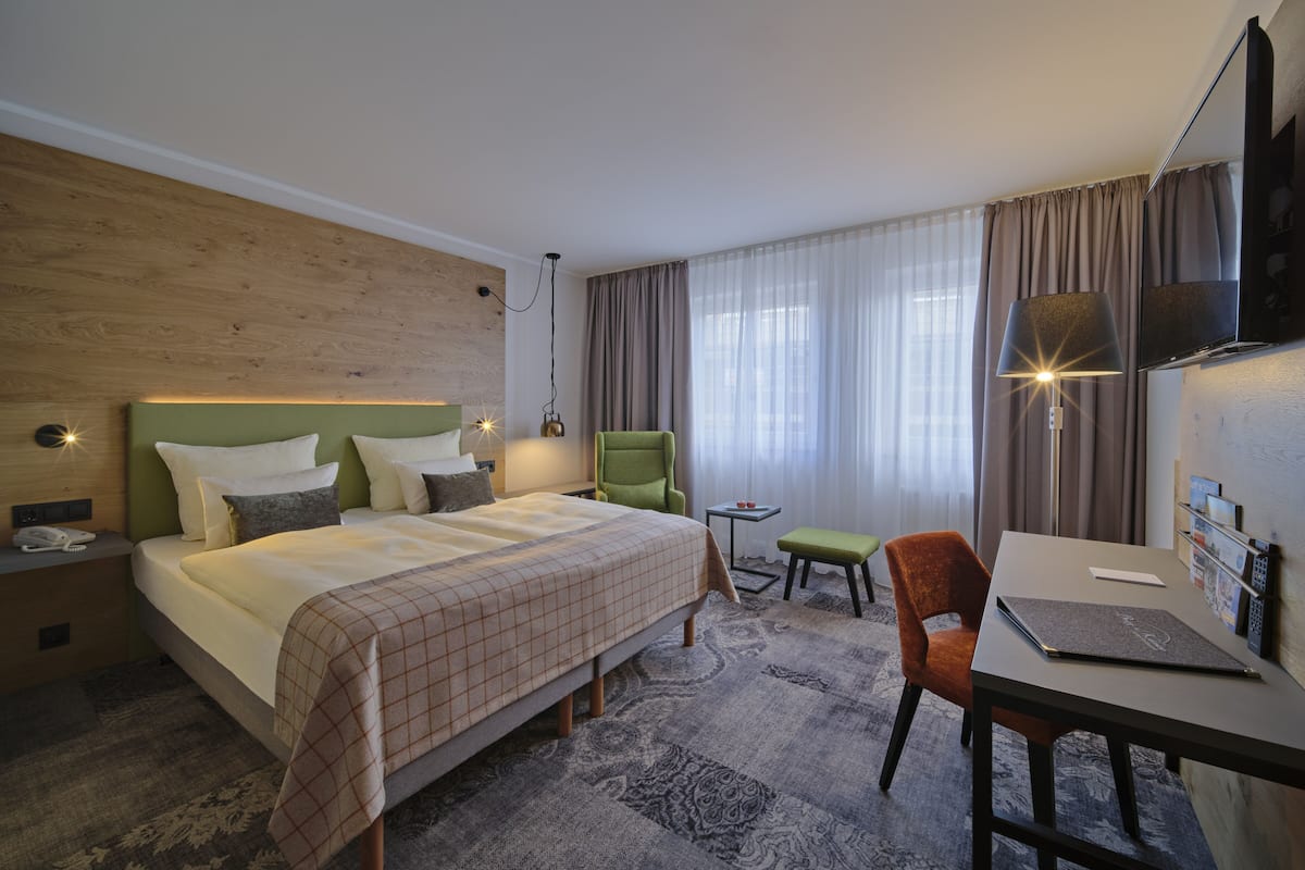 Ein Hotelzimmer mit einem Bett, einem Schreibtisch, einem Stuhl, einem Fernseher und einer Lampe.