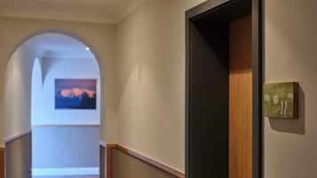 A hallway with a wooden door, a number plaque, and a painting on the wall.