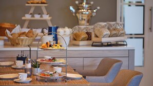 A breakfast buffet setup with various food items and a tiered display of pastries.