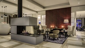 A modern living room with a fireplace, comfortable seating, and a large window.