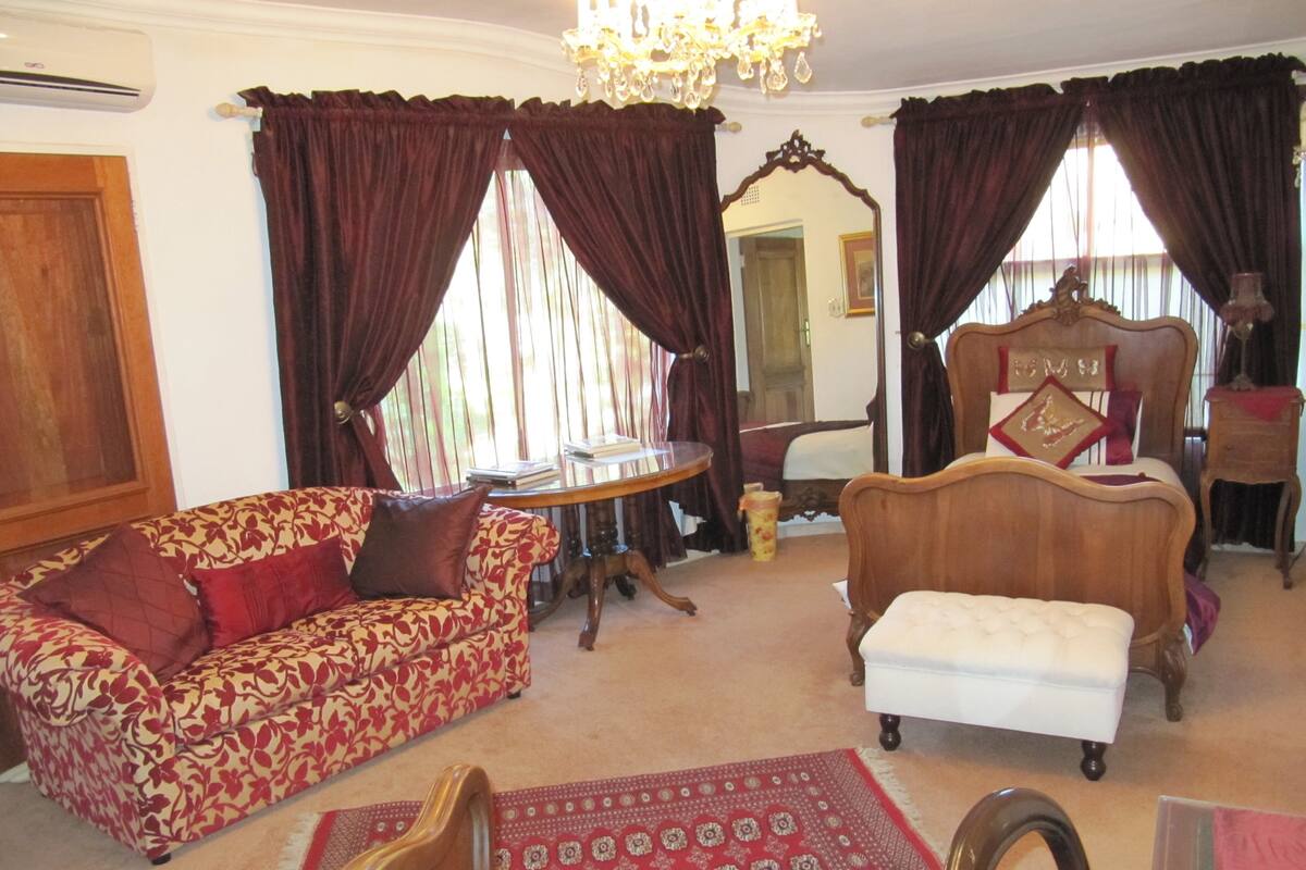 A traditional room with a sofa, a small table, a chair, and a bed.