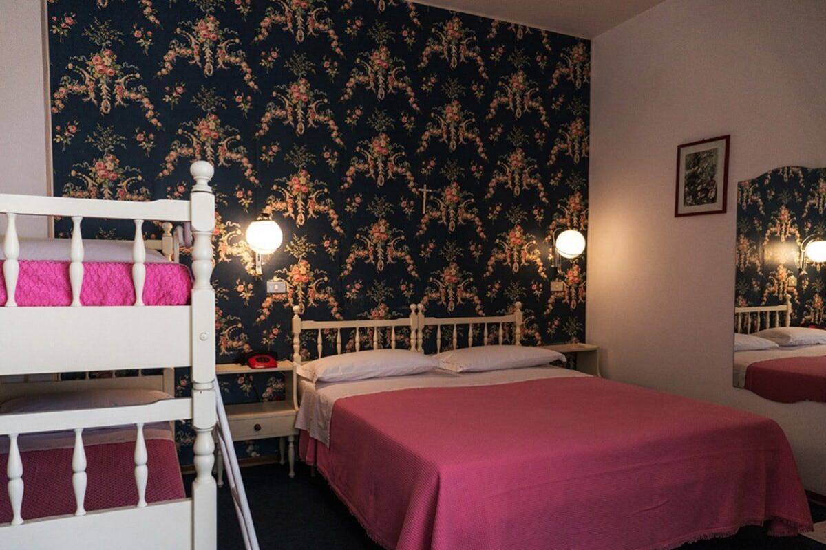 A bedroom with a bunk bed, a single bed, and two bedside lamps.