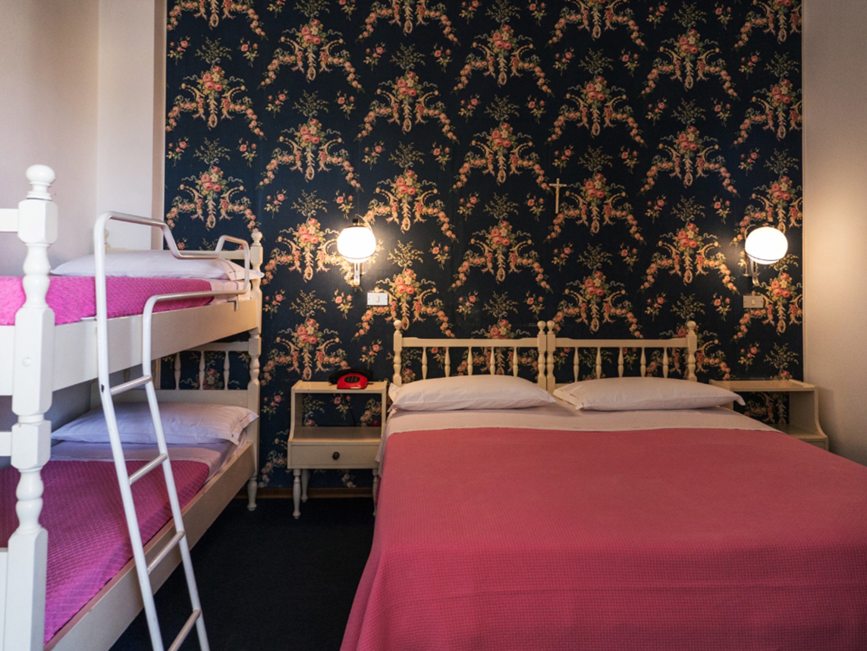Ein Zimmer mit einem Etagenbett, einem Einzelbett und einem Nachttisch mit Lampe.